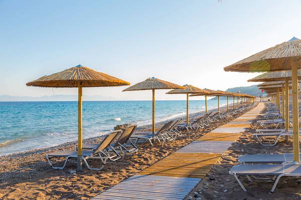 Reihe von Sonnenliegen und Sonnenschirmen am Strand des Akti Imperial Deluxe Resorts & Spa.