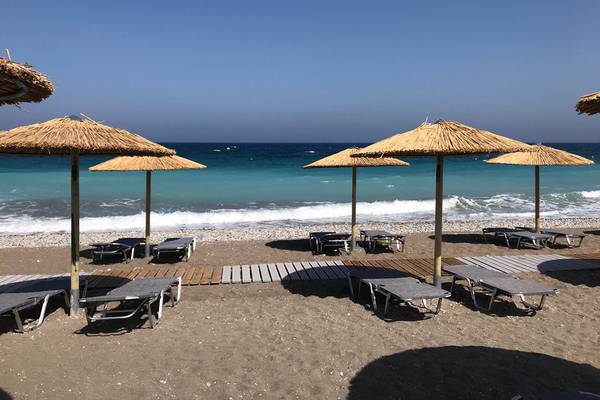 Strandszene mit Sonnenliegen unter Strohschirmen im Akti Imperial Deluxe Resort & Spa.
