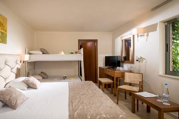 Doppelzimmer im Bella Beach Hotel mit Doppelbett und Stockbett, Nachttisch und Schreibtisch.