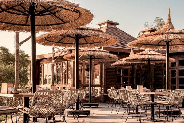 Außenbereich des Cook's Club El Gouna mit Tischen, Stühlen und Strohdächern.