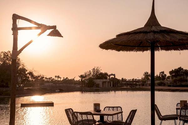Terrasse mit Tischen und Stühlen bei Cook's Club El Gouna bei Sonnenuntergang.