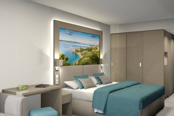 Ein modernes Hotelzimmer im Bretanide Sport & Wellness Resort mit einem großen Bett, Schreibtisch und Panoramafenster.