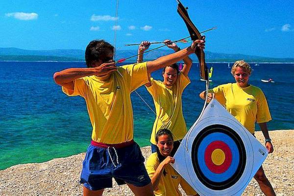 Gruppe junger Leute beim Bogenschießen am Strand im Bretanide Sport & Wellness Resort.