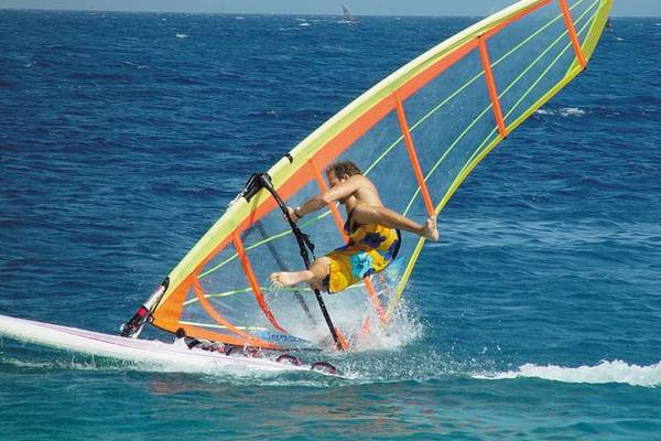 Windsurfer auf offenem Ozean, blaues Wasser und blauer Himmel im Hintergrund