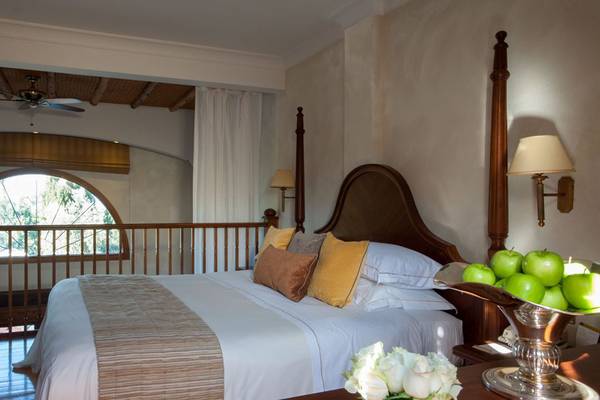 Schlafzimmer im Elysium Hotel mit Bett, Obstschale und Fenstern.