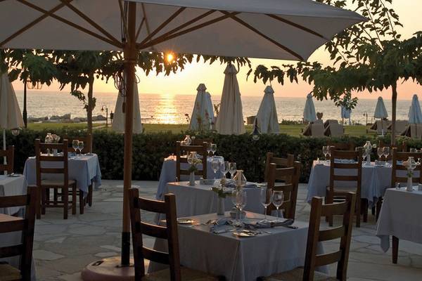 Elysium Hotel Terrasse mit Tischen und Stühlen bei Sonnenuntergang am Meer