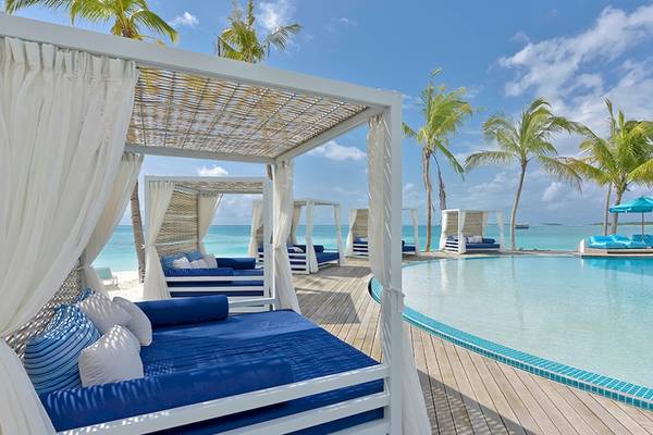 Außenbereich des Kandima Maldives mit Pool, Loungebetten und Palmen