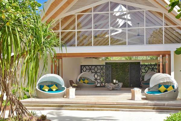 Außenbereich des Kandima Maldives Hotels mit überdachten Sitzbereichen und Pflanzen.