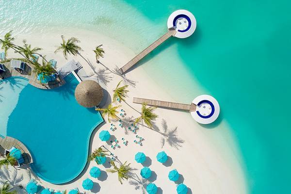 Luftaufnahme des Kandima Maldives Resorts mit Infinity-Pool, Sonnenliegen und Palmen