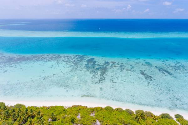 Luftaufnahme des Kandima Maldives zeigt kristallklares Wasser und weißen Sandstrand.