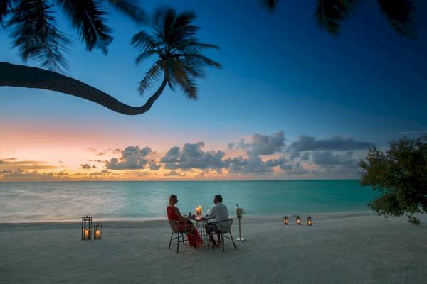 Zwei Personen beim Essen auf dem Strand bei Sonnenuntergang im Kandima Maldives
