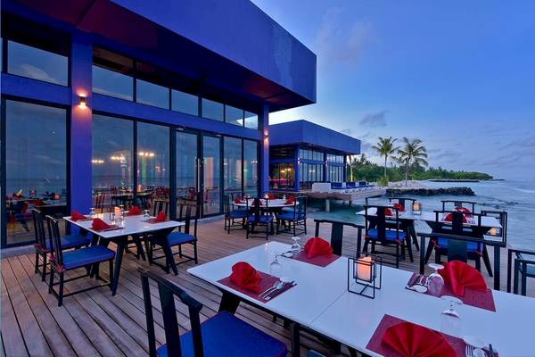 Abendessen auf Holzdeck im Kandima Maldives Hotel mit Blick auf das Meer und Inseln.