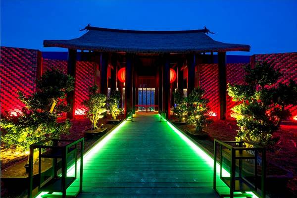 Eingang des Kandima Maldives Hotels bei Nacht mit grünen und roten Lichtern.