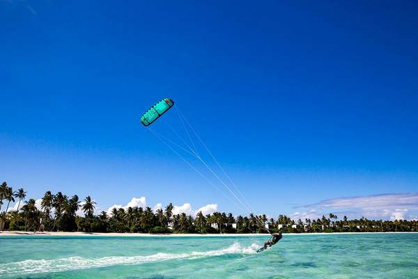 Ein Kitesurfer am Strand von Kandima Maldives, mit einer blauen Kite in der Luft.