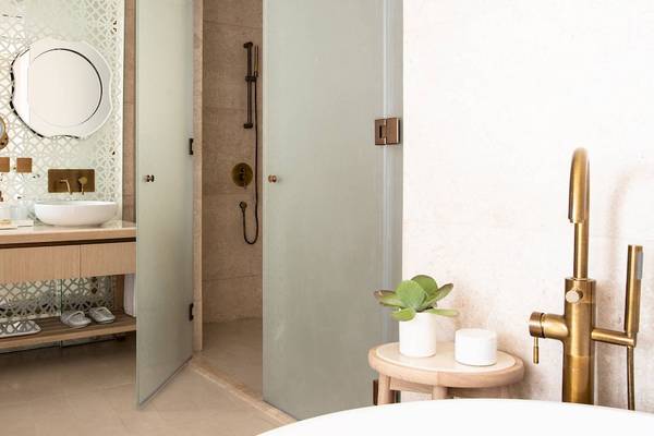 Badezimmer im Jumeirah at Saadiyat Island Resort mit zwei Waschbecken, Regendusche und goldenen Armaturen.