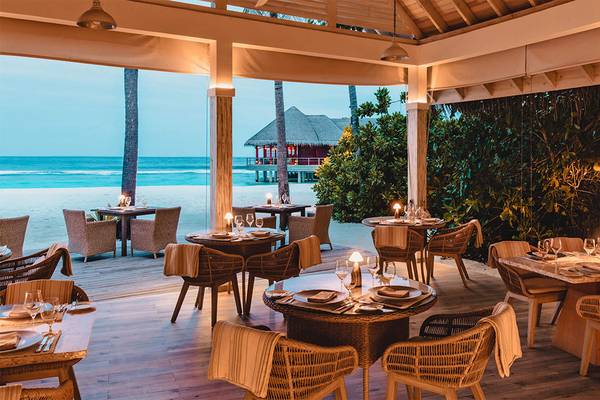 Außenbereich des Finolhu Baa Atoll Maldives Hotels mit Tischen und Stühlen am Meer.