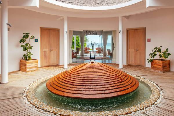 Innenbereich des Finolhu Baa Atoll Maldives Hotels mit einem großen Brunnen und Ausblick auf das Meer.