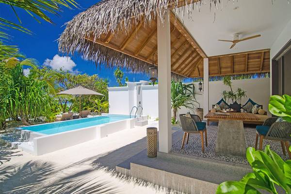 Außenpool und Terrasse des Finolhu Baa Atoll Maldives Hotels mit Loungemöbeln und Pflanzen.