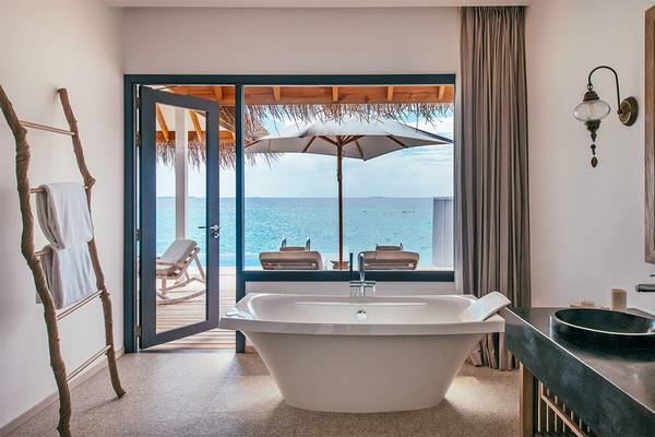 Badezimmer der Suite im Finolhu Baa Atoll Hotel mit Blick auf das Meer.