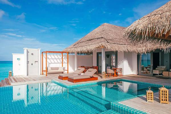 Poolbereich der Finolhu Baa Atoll Maldives Villa mit Lounge-Stühlen und Blick auf das Meer.