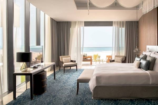 Schlafzimmer im Jumeirah at Saadiyat Island Resort mit Meerblick, großem Bett, Schreibtisch und Lampen.