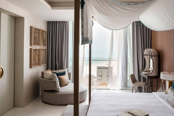 Ein modernes Hotelzimmer mit Aussicht auf das Meer, inklusive eines großen Himmelbetts, einer Sitzecke und einem Schreibtisch.