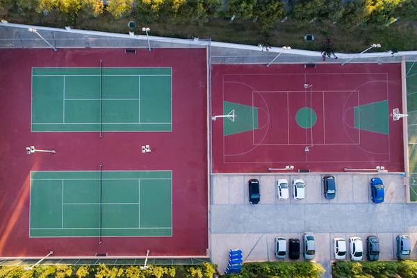 Luftaufnahme der Sportanlage des Horizon Beach Resorts mit Tennis- und Basketballplätzen und geparkten Autos.
