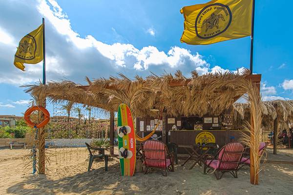 Strandstand des Horizon Beach Resorts mit Palmenblätterdach, Flaggen und Strandmöbeln.