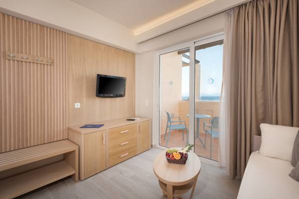 Innenansicht des Horizon Beach Resort Zimmers mit Fernseher, Tisch, Obstkorb und Balkon.