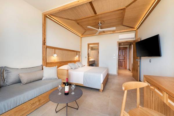 Innenansicht eines Horizon Beach Resort Zimmers mit Bett, Couch, Tisch und Fernseher.