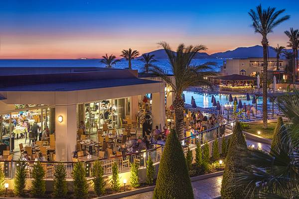 Außenbereich des Horizon Beach Resort bei Sonnenuntergang mit Blick auf das Meer und die Berge.