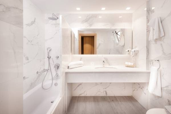 Innenansicht eines Badezimmers im Horizon Beach Resort mit weißen Marmorfliesen und einer Badewanne.