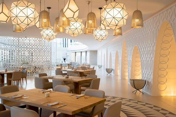 Innenansicht des Restaurants im Jumeirah at Saadiyat Island Resort mit geometrischen Mustern und hängenden Lampen.