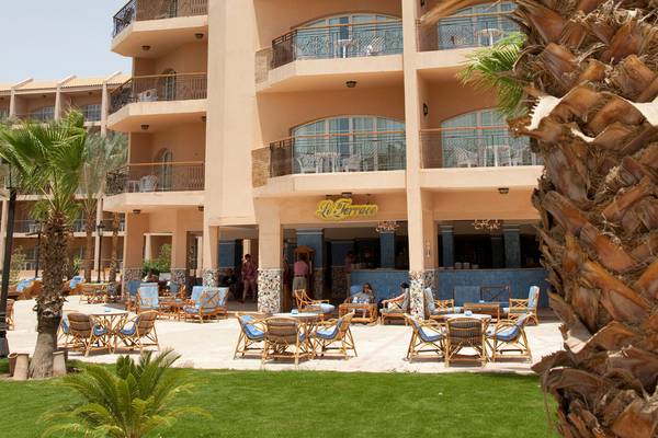 Terrasse des Siva Grand Beach Hotels mit Tischen, Stühlen und Palmen