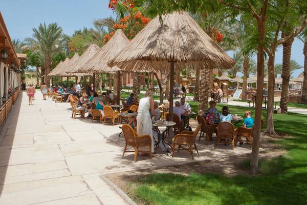 Gäste sitzen unter Strohdächern auf der Terrasse des Siva Grand Beach Hotels.