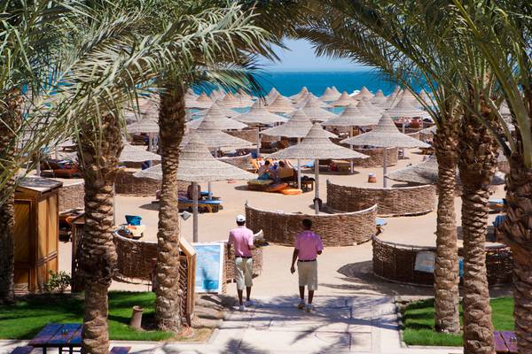 Blick auf den Strand des Siva Grand Beach Hotels mit Palmen und Sonnenschirmen.