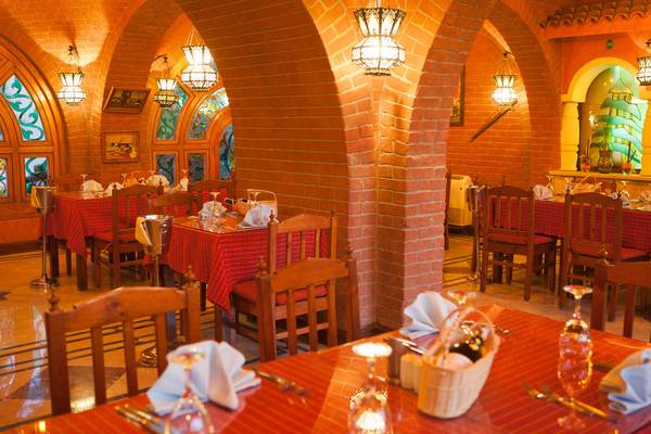 Innenansicht des Restaurants im Siva Grand Beach Hotel mit roten Tischdecken und viktorianischen Stühlen.