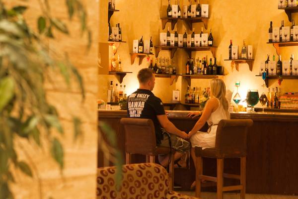 Paar sitzt an der Bar im Siva Grand Beach Hotel mit vielen Flaschen im Hintergrund.