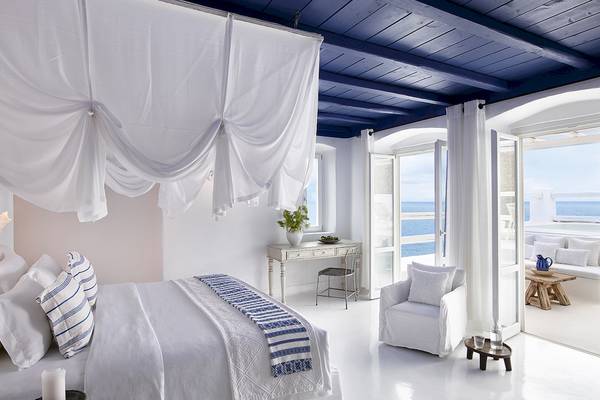 Schlafzimmer im Grecotel Mykonos Blu mit Blick auf das Meer und einer weißen Einrichtung.