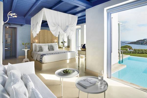 Innenansicht der Suite im Grecotel Mykonos Blu mit Bett und Blick auf den Pool.