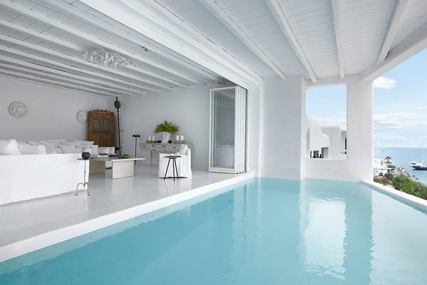 Innenpool im Grecotel Mykonos Blu mit weißem Interieur und Blick auf das Meer