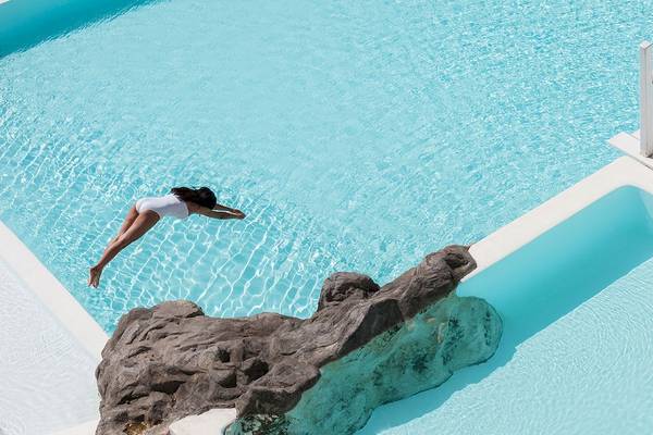 Frau springt in den Pool im Grecotel Mykonos Blu Hotel.
