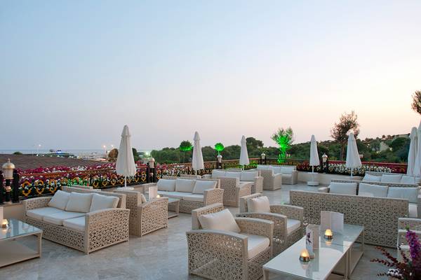 Terrasse des Diamond Excellence Resort & Spa mit weißen Möbeln und geöffneten Sonnenschirmen.