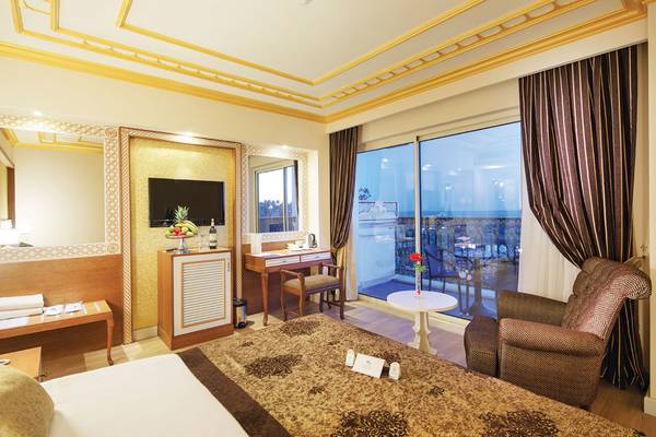 Ein elegantes Hotelzimmer im Diamond Excellence Resort & Spa mit großem Bett, Schreibtisch und Balkon.