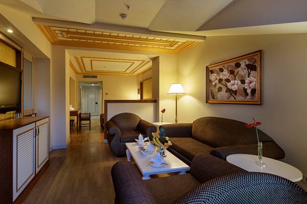 Innenansicht der Suite im Diamond Excellence Resort & Spa mit Fernseher, Sofas und Tisch.