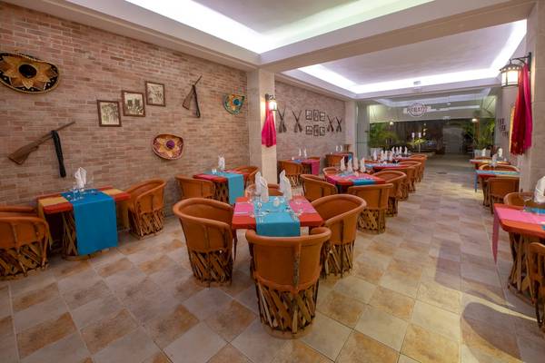 Innenansicht des Restaurants im Viva Wyndham V Heavens Hotel mit braunen Stühlen und blauen Tischdecken.