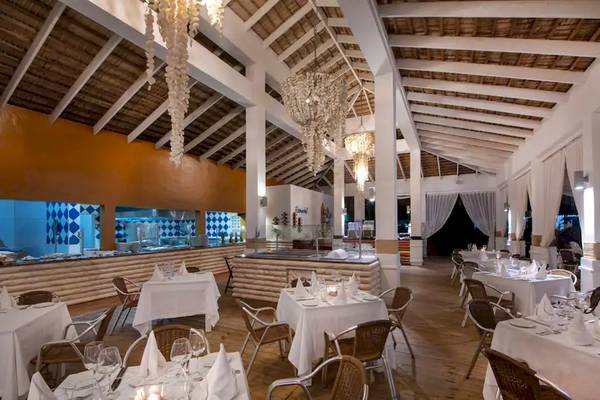 Restaurant im Viva Wyndham V Heavens Hotel mit weißen Tischen und Stühlen, Holzboden und Kronleuchtern.