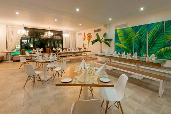 Innenansicht des Viva Wyndham V Heavens Restaurants mit gedeckten Tischen und tropischen Wandgemälden.
