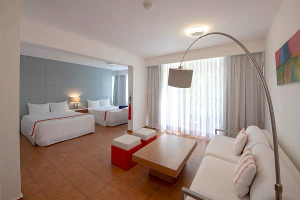 Innenansicht einer Hotelsuite im Viva Wyndham V Heavens mit zwei Betten, Sofa und Tisch.