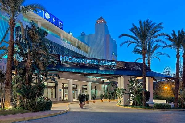 Eingang des H10 Estepona Palast Hotels mit Palmen und Beleuchtung